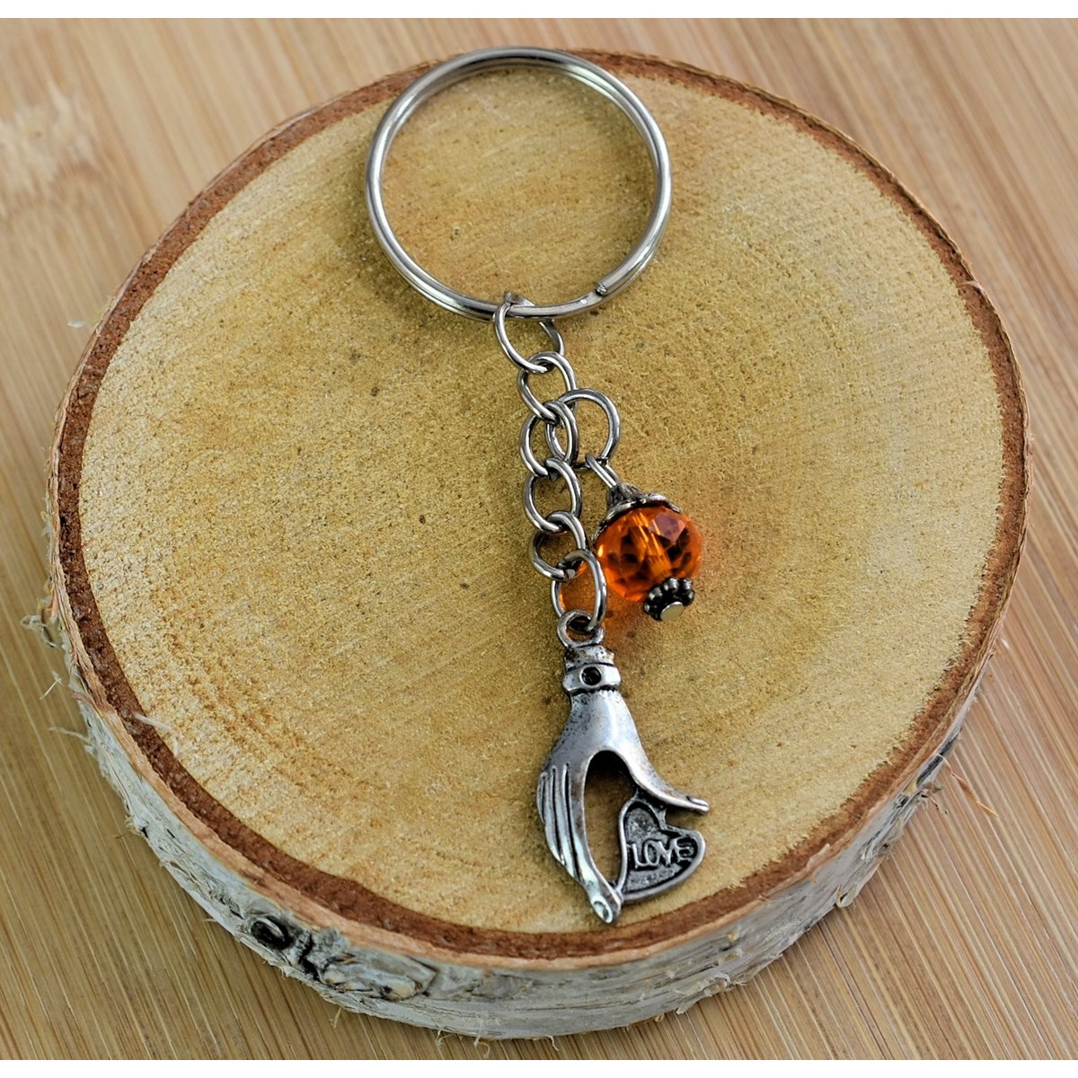 Porte-clés main qui tient un coeur love argentée et perle à facettes orange - vue 3