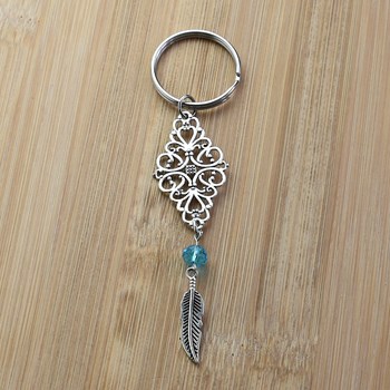 Porte-clés losange filigrane perle à facette bleue et plume pendante argenté